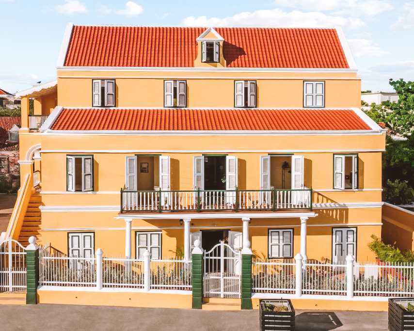 Fachada colorida do NEW Drift Hotels entre prédios históricos de Curaçao